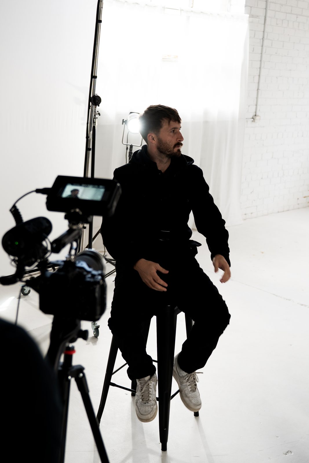 A crew member seated on a stool in the studio, a rigged camera in the foreground